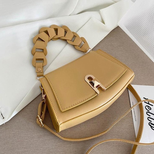 sac à main à bandoulière tressée couleur beige avec chaîne décorative sur une surface neutre
