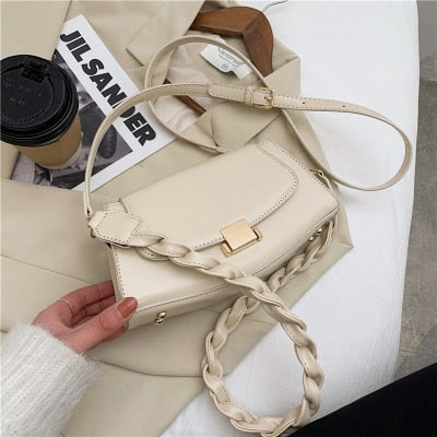 Sac à bandoulière twist strap shoulder bag en cuir beige avec chaîne torsadée, mode féminine.