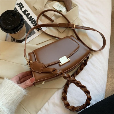 Sac à bandoulière en simili cuir marron avec sangle tressée, parfait pour un look décontracté ou formel.