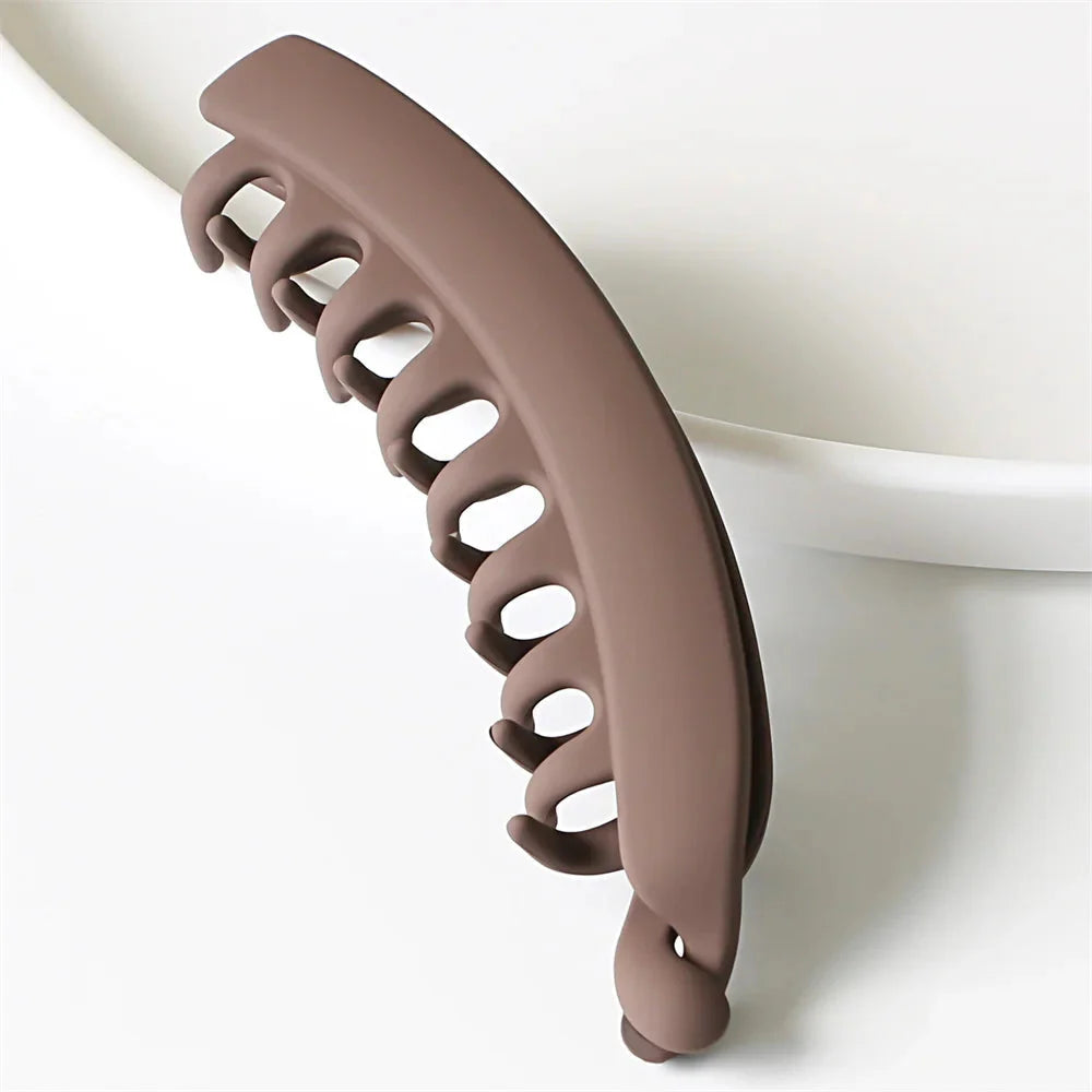 Barrette cheveux banane couleur unie en plastique marron, idéale pour un maintien doux et élégant.