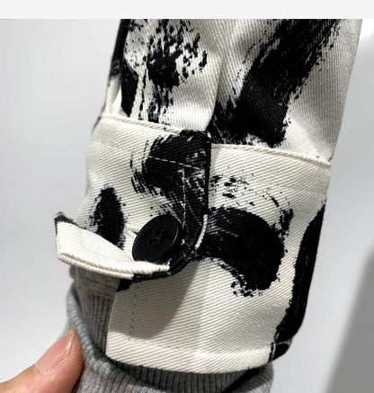 détail de chemise à manches longues hommes avec motif noir et blanc, mettant en avant le bouton et le tissu